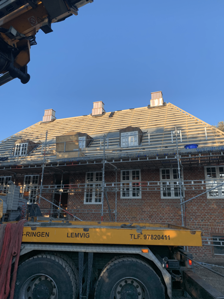 Tagrenovering på murstenshus med stillads og kran